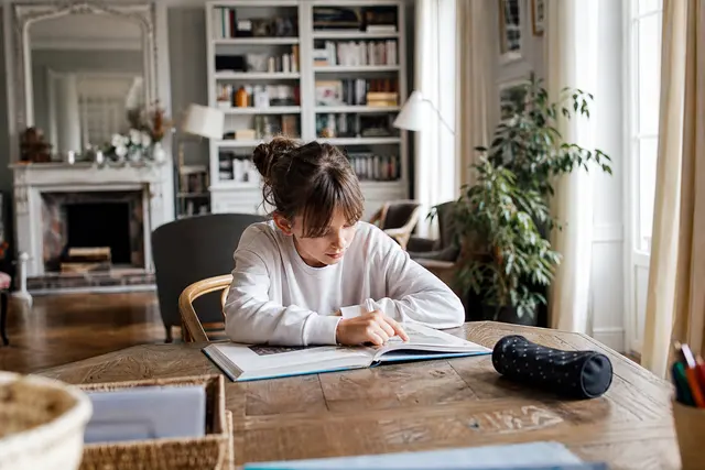 Enfant assis seul dans un salon lumineux, jouant calmement pendant l'absence d'un parent