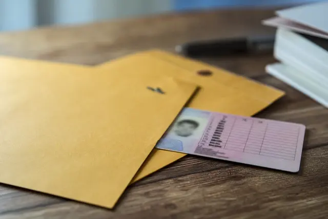 Enveloppe administrative posée sur une table à côté d'un permis de conduire