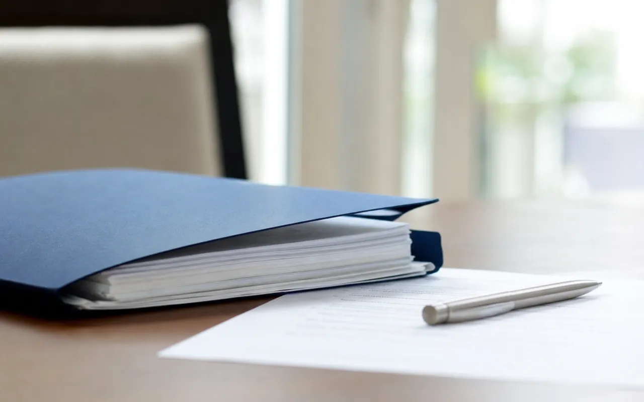 Dossier de prêt immobilier et contrat d'assurance posés sur une table avec un stylo