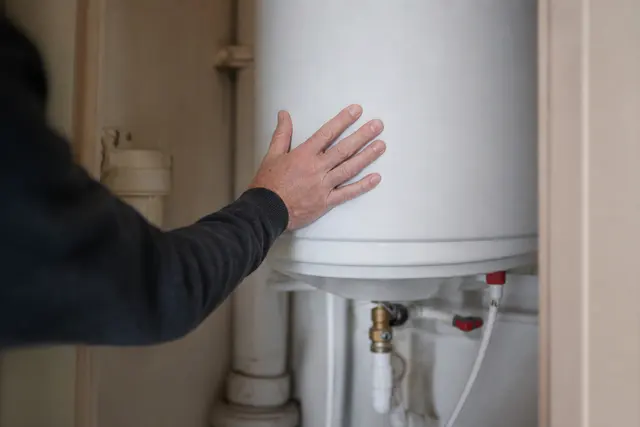 Chauffe-eau électrique blanc installé dans un cellier, gros plan sur le ballon et la tuyauterie