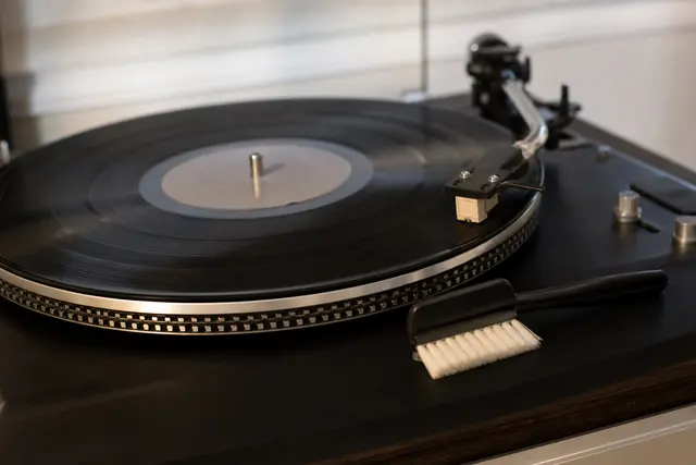 Disque vinyle noir posé sur une platine, brosse anti-statique à proximité
