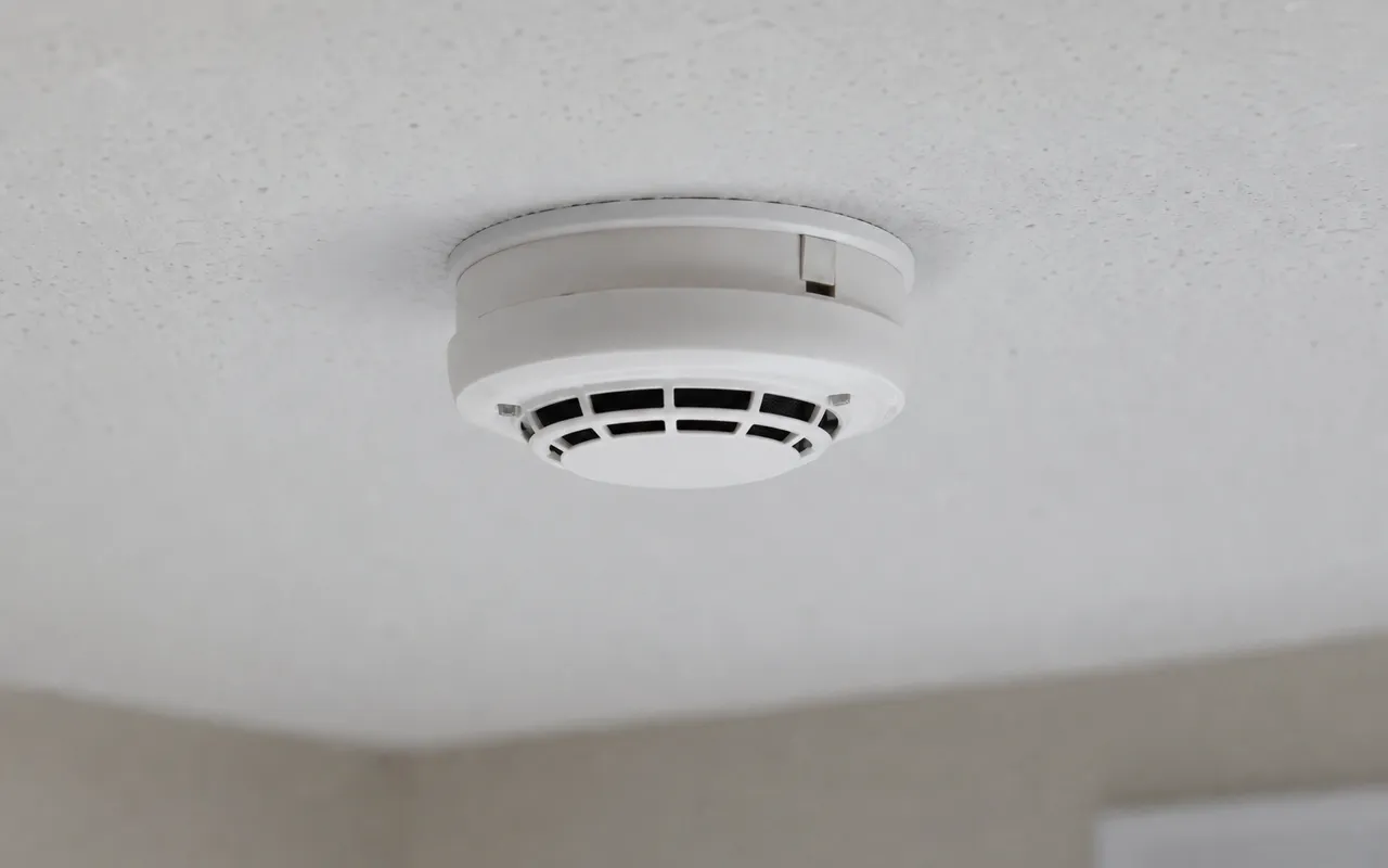 Détecteur de fumée blanc fixé au plafond d'une pièce