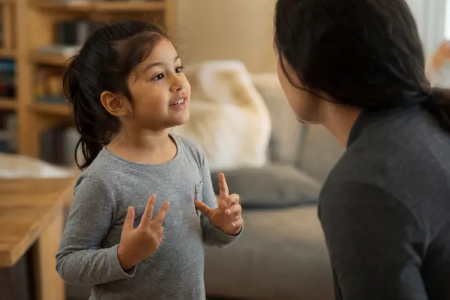 Enfant en train de parler et de jouer avec un adulte, moment de complicité