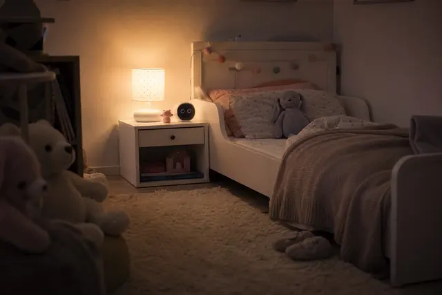 Chambre d'enfant le soir avec une veilleuse allumée près d'un lit, ambiance calme et tamisée