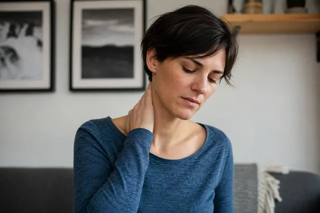 Personne touchant doucement son cou d'un côté, expression de gêne légère