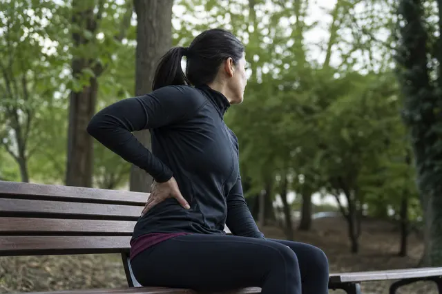 Coureur assis sur un banc après l'effort, main posée sur le flanc