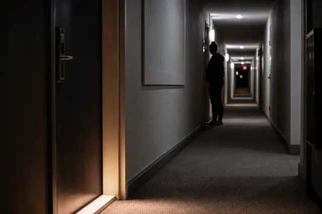 Appartement la nuit avec de la lumière filtrant sous une porte, illustrant une nuisance sonore de voisinage