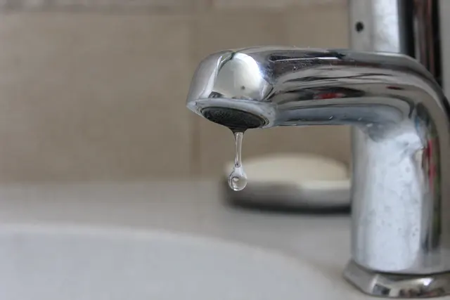 Gros plan sur un robinet de salle de bain avec une goutte d'eau suspendue au bec