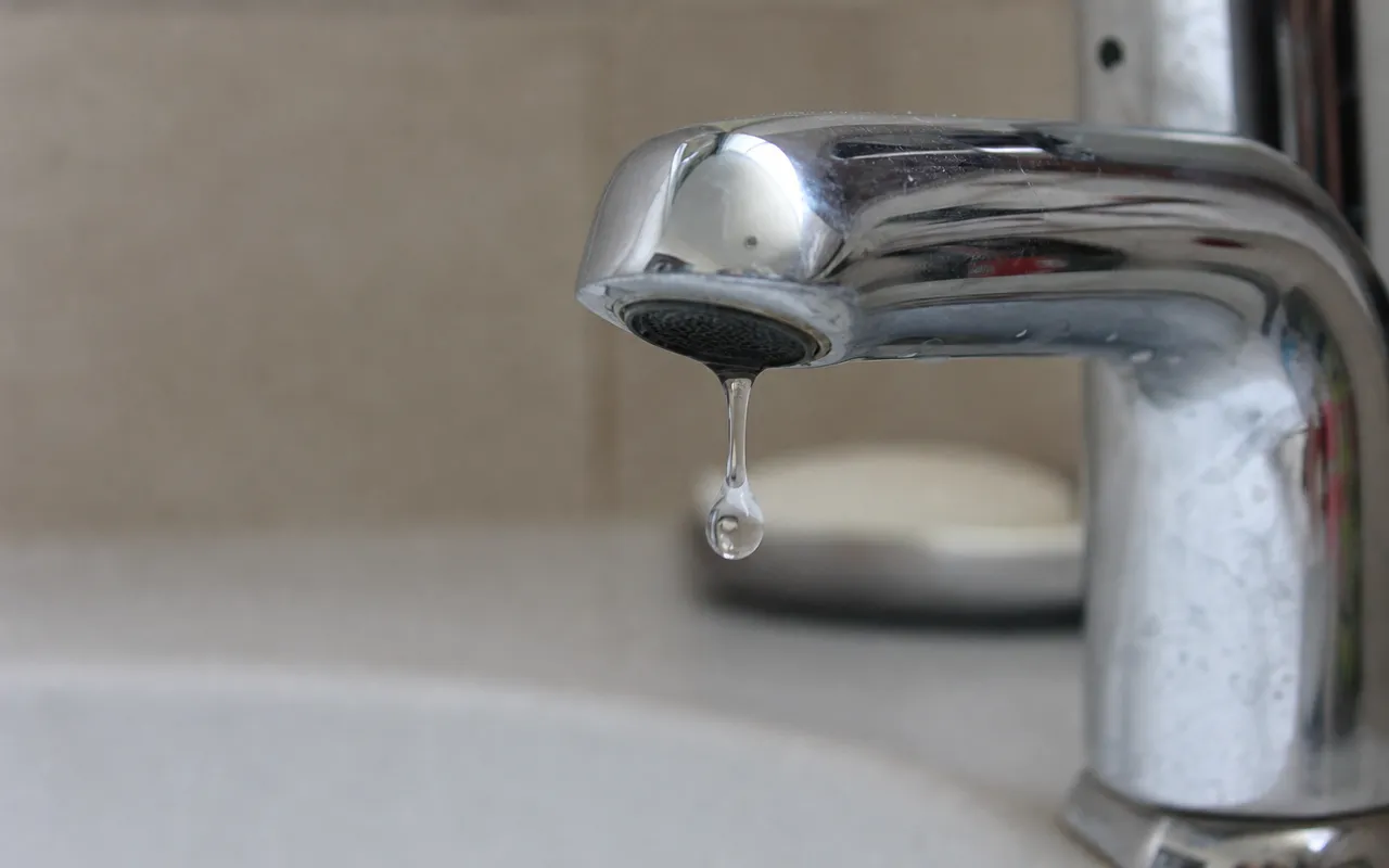 Gros plan sur un robinet de salle de bain avec une goutte d'eau suspendue au bec