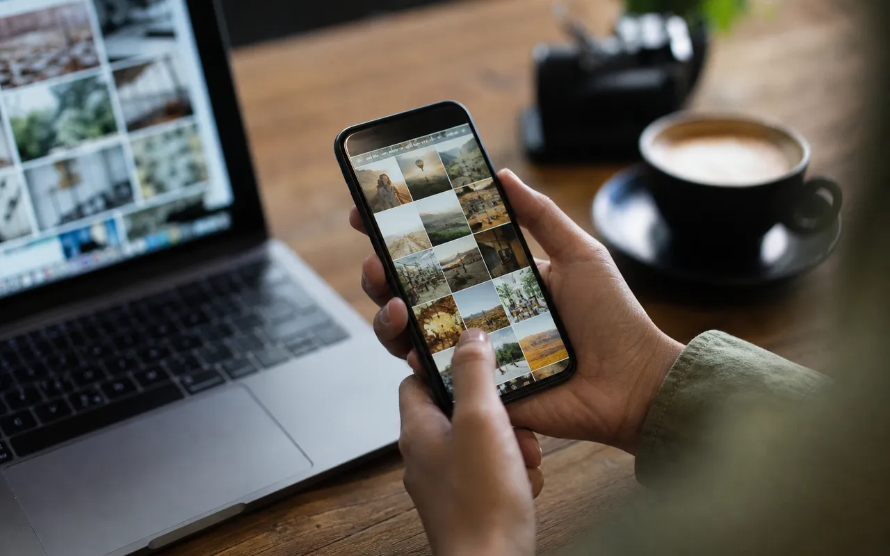 Personne tenant un smartphone et faisant défiler une galerie de photos, écran allumé dans une lumière douce d'intérieur