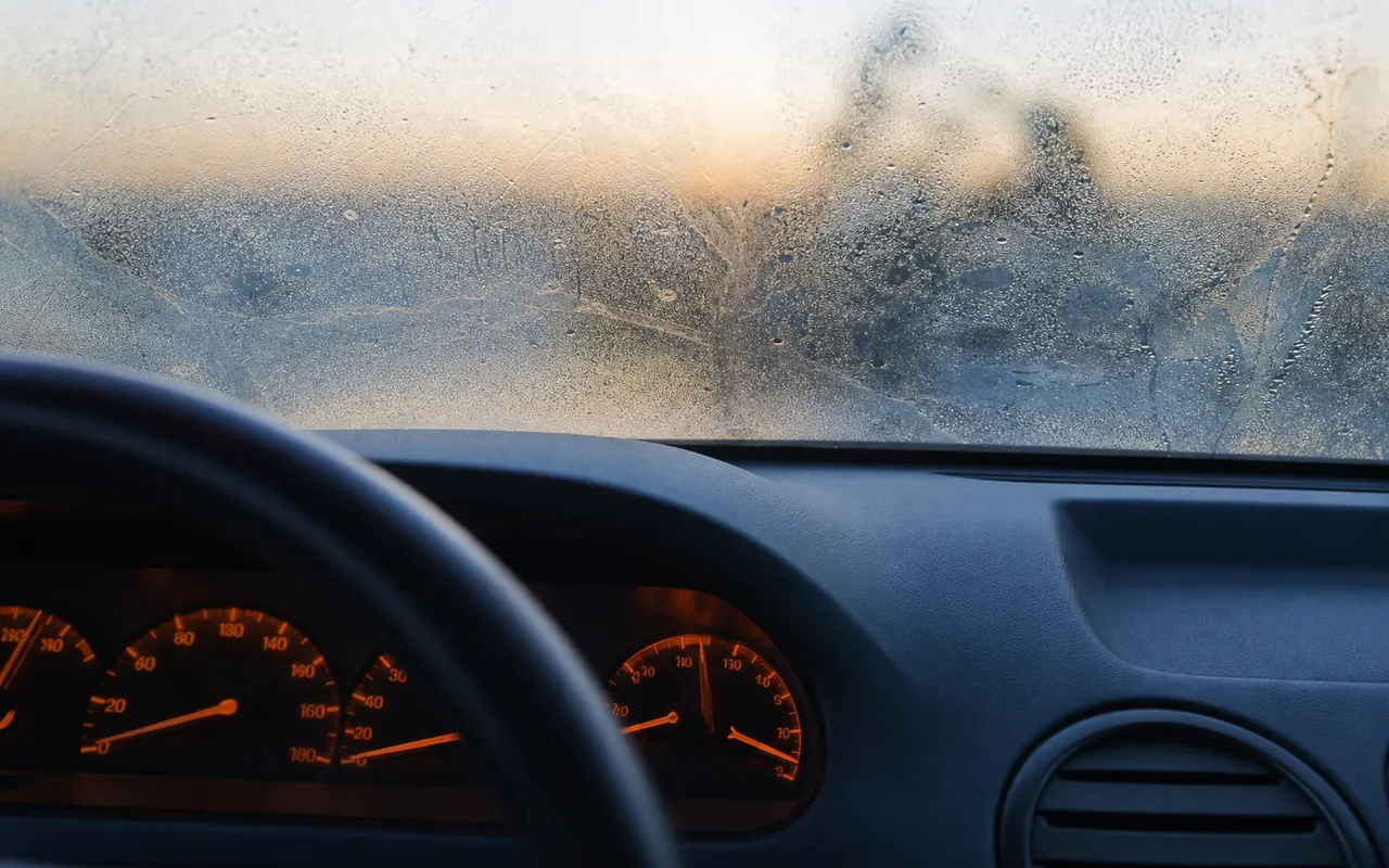 Intérieur d'un habitacle de voiture avec le tableau de bord allumé par un matin froid