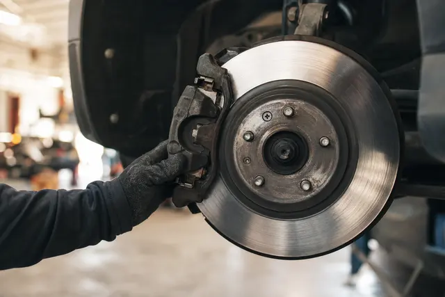 Gros plan sur une jante et un disque de frein automobile en cours d'inspection dans un garage